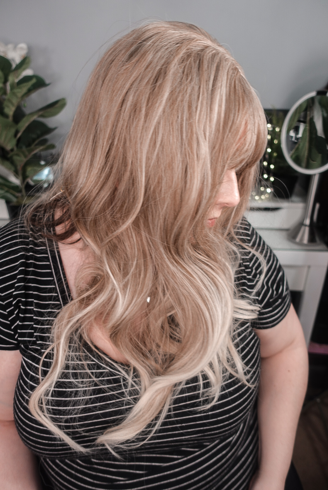 Haircube blonde synthetic wig side view - long wavy with curtain bangs, worn by Neveen Wood